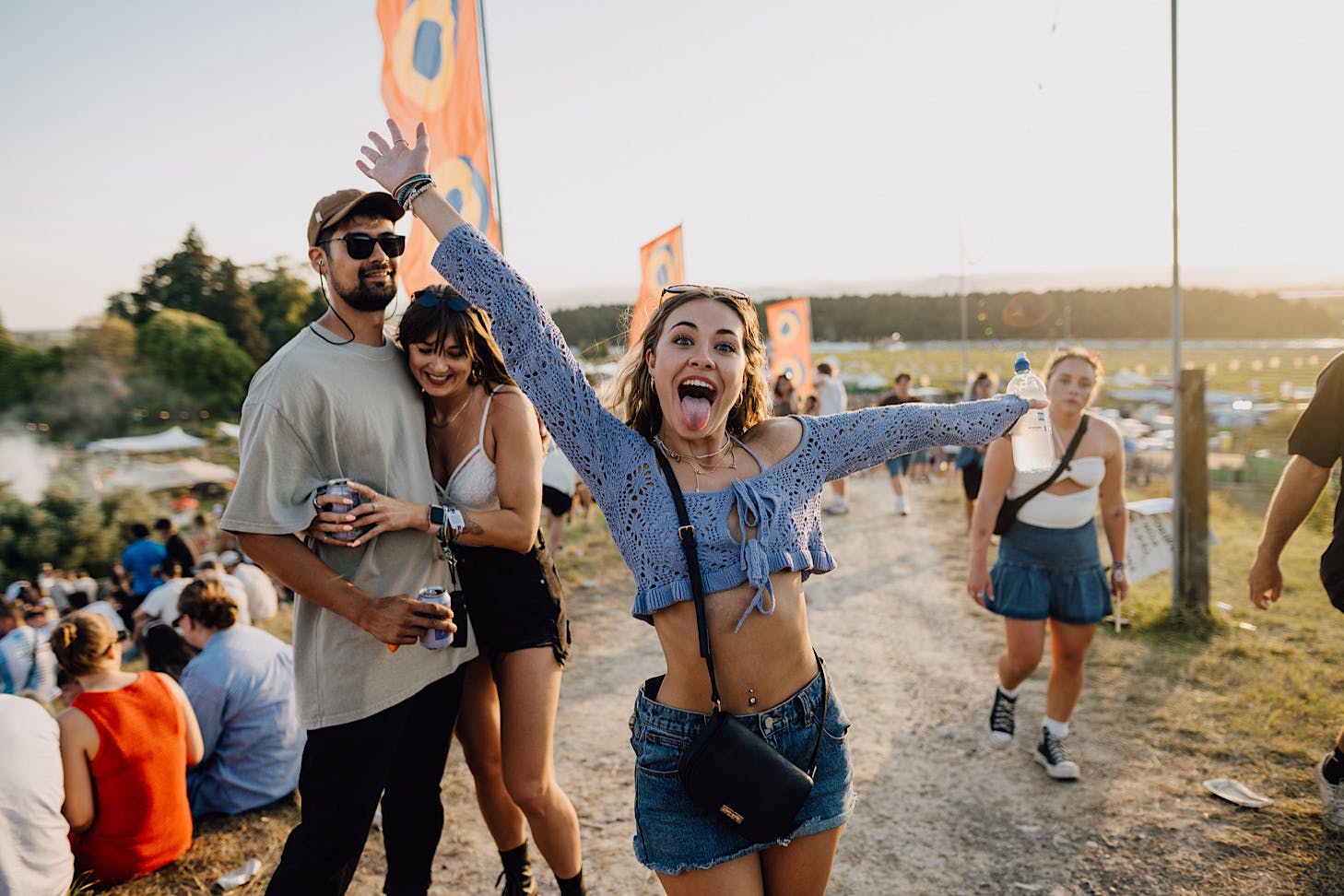 A woman in a purple crop top and jean mini skirt sticks her tongue out happily.